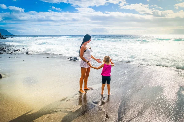 Sağlıklı, mutlu bir aile annesi ve kızı deniz kenarında esneme egzersizleri yapıyor. — Stok fotoğraf