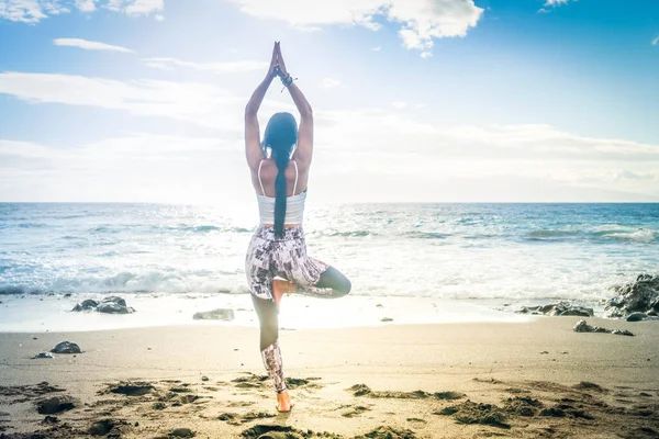 Woman in sport clothes practicing yoga and meditating on beach in morning — Stock Photo, Image