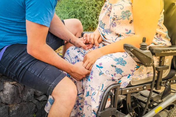 Niepełnosprawna kobieta na wózku inwalidzkim trzymająca za rękę swojego chłopaka podczas randek na świeżym powietrzu — Zdjęcie stockowe