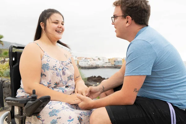 Niepełnosprawna kobieta na wózku inwalidzkim trzymająca za rękę swojego chłopaka podczas randek na świeżym powietrzu — Zdjęcie stockowe