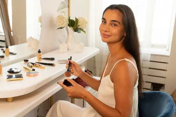 Morena mujer con el pelo largo y oscuro y la piel limpia haciendo la rutina de maquillaje —  Fotos de Stock