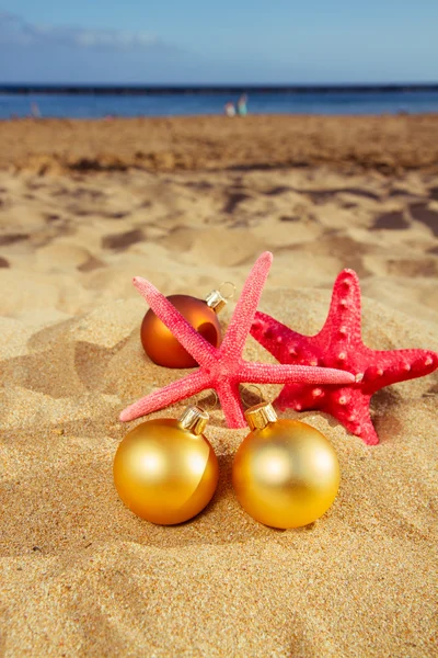 Christmas balls with starfish on beach — Stock Photo, Image