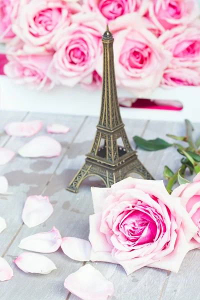 Roze rozen met eiffel tour op tafel — Stockfoto