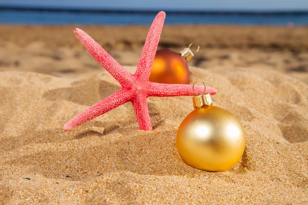 Christmas balls with starfush on beach — Stock Photo, Image