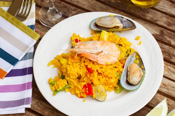 Paella servida en plato sobre mesa de madera —  Fotos de Stock