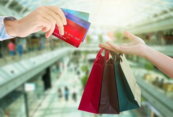 Manos sosteniendo bolsas y tarjetas de crédito — Foto de Stock