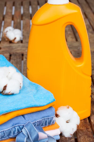 Orange bottle of detergent and cotton clothes — Stock Photo, Image