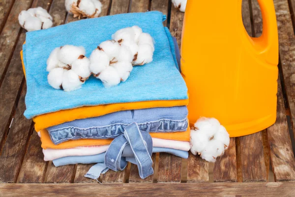 Orange bottle of detergent and cotton clothes — Stock Photo, Image