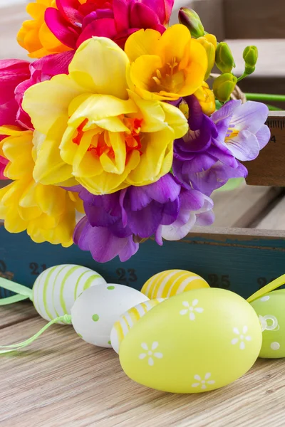 Easter eggs and posy  of spring flowers on wooden table — Stock Photo, Image