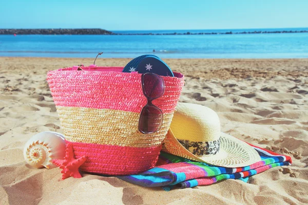 Strwa bag with sunbathing accessories on sandy beach — Stock Photo, Image