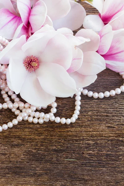 Flores de magnólia com pérolas em mesa de madeira — Fotografia de Stock