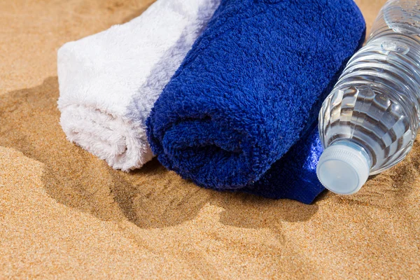 Πετσέτες και μπουκάλι νερό στην άμμο — Φωτογραφία Αρχείου