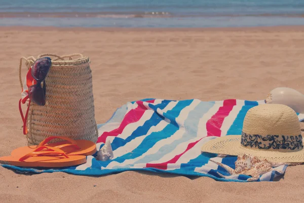 Hasır çanta kumlu plajda güneşlenirken aksesuarları — Stok fotoğraf