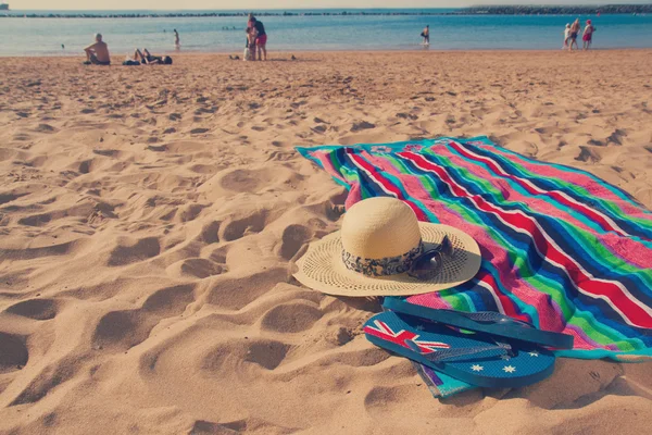 Handtuch und Sonnenschutz am Sandstrand — Stockfoto