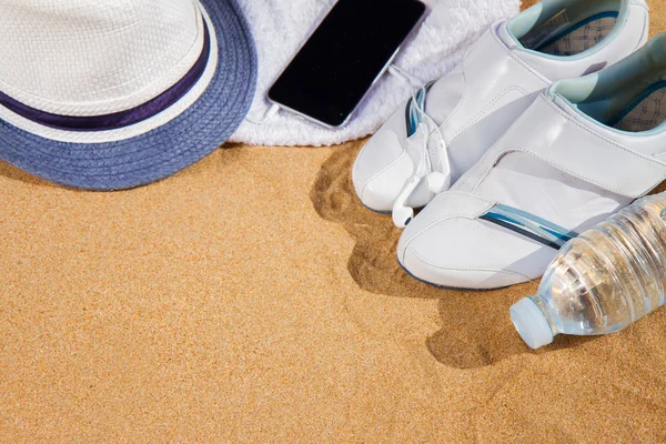 Bílé tenisky s kloboukem v písku — Stock fotografie