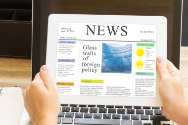 hands holding tablet with news site