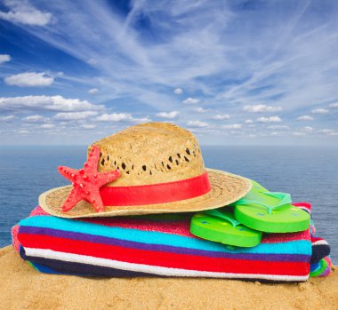 kum üzerinde hasır şapka ve güneşlenme aksesuarlar