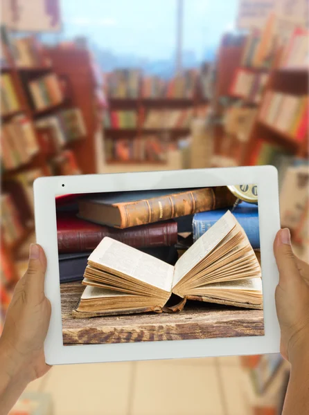 Tablet met bibliotheek planken op achtergrond — Stockfoto