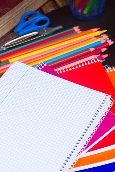 Empty notebook and set of colorful pencils on black board — Stock Photo, Image