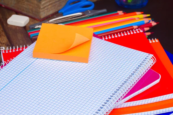 Empty notebook and set of colorful pencils on black board — Stock Photo, Image