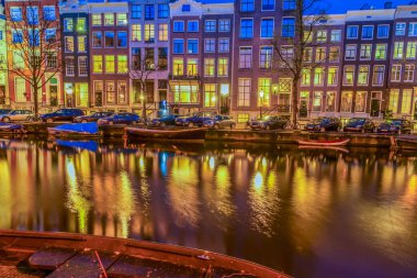 Tipik Hollanda evleri ile ışıklı windows yansımaları ile kanal üzerinde gece, Amsterdam, Hollanda