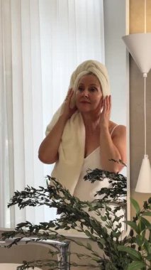 Neşeli bir kadın huzurlu, bitkisel banyosunda cilt bakımının keyfini çıkartıyor.