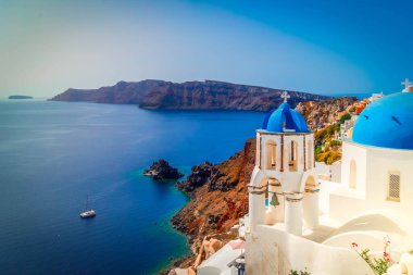 Yunanistan 'ın deniz ve kalderasına karşı mavi kubbeli ve beyaz duvarlı geleneksel Yunan köyü Oia of Santorini