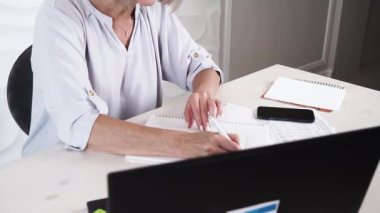 Modern dizüstü bilgisayarla çalışan ve faturalarını, teknolojisini ve yaşlılar yaşam tarzını kontrol eden yaşlı bir kadın.