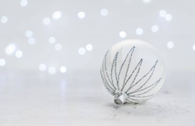 Arka planda bir beyaz ve gümüş top ve Noel ışıkları ile Noel sahne