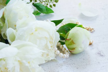 Beyaz taze Şakayık çiçekleri buketi inci kuyumculuk iplikçiğe yaşlı beyaz ahşap masa ile