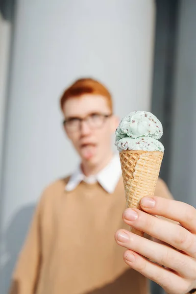 Cone de sorvete perto da câmera realizada pelo jovem excêntrico. Rosto desfocado — Fotografia de Stock