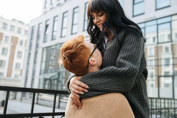 Joven hombre sosteniendo a su chica en el aire por sus muslos, ella es feliz. Ángulo ascendente — Foto de Stock