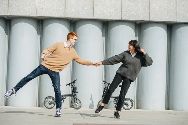 Pareja sonriente divirtiéndose, de pie sobre un pie, tirándose unos a otros. —  Fotos de Stock