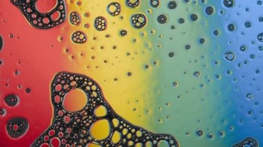 Gökkuşağının arka planında bir sürü küçük kabarcıklı köpük akışı. Stüdyo soyut video.