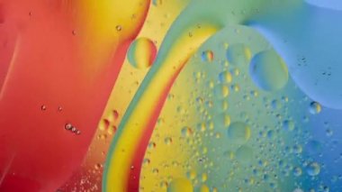 Gökkuşağının arka planıyla karışım sırasında sıvı baloncukların yakın plan görüntüsü. Yüksek kaliteli makro video. Soyut kavram
