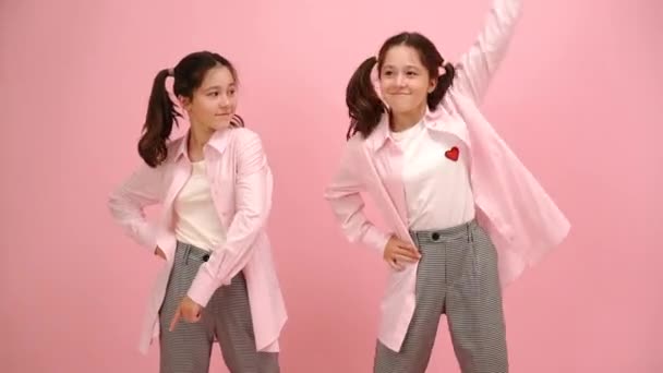Mooie Tweelingzusjes Die Vrolijk Glimlachen Naar Verschillende Richtingen Wijzen Roze — Stockvideo