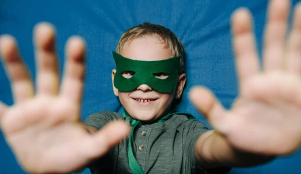 Sonriente niño con máscara acostado boca arriba en la superficie del trampolín, bloqueando la cámara — Foto de Stock