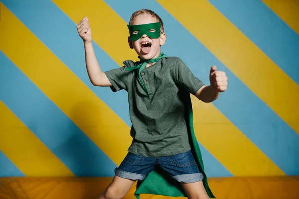 Wild expressiv pojke i mask hoppar på studsmatta i nöjescentrum — Stockfoto