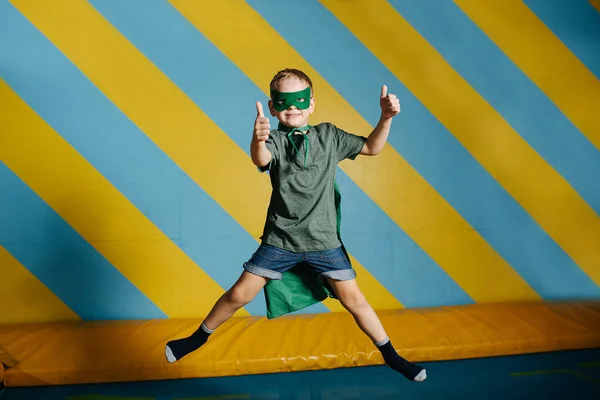 Niño confiado saltando en el trampolín en el centro de entretenimiento con los pulgares arriba —  Fotos de Stock