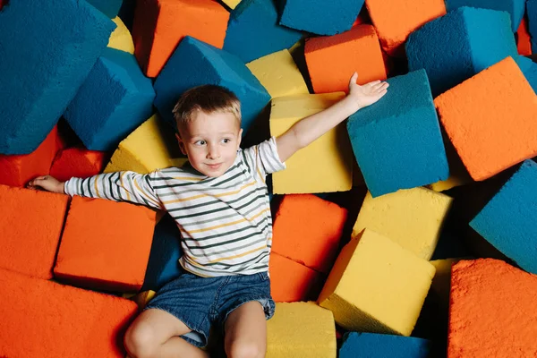 Випадковий маленький хлопчик в багатокольоровому басейні м'якого кубика в розважальному центрі — стокове фото