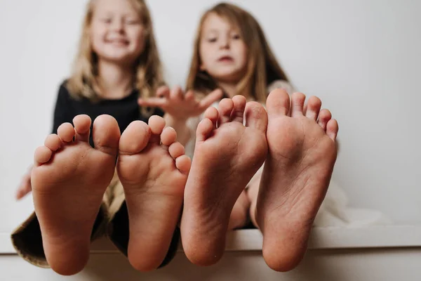 Kids hold feet close up to the camera. Their blurred faces in a background. — Stock Photo, Image