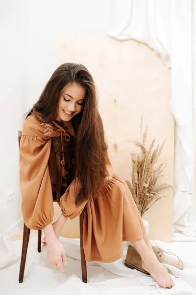 Shy carefree woman with beautiful features sitting cross-legged on a chair — Stock Photo, Image