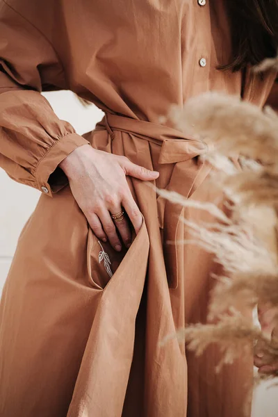 Close up afbeelding van een vrouw in een lichtbruine jurk steken hand in een zak. — Stockfoto