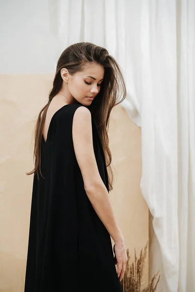 Stunning beautiful woman wearing a black V-neck dress. View from the side. — Stock Photo, Image