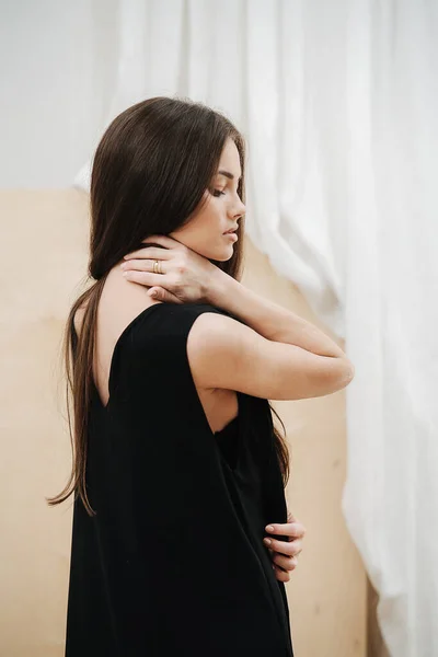 Jeune belle femme portant une robe noire à col V. Vue de côté. — Photo