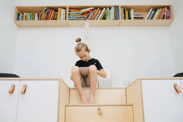 A boy draws with a pencil sitting in a childrens room at home — 스톡 사진