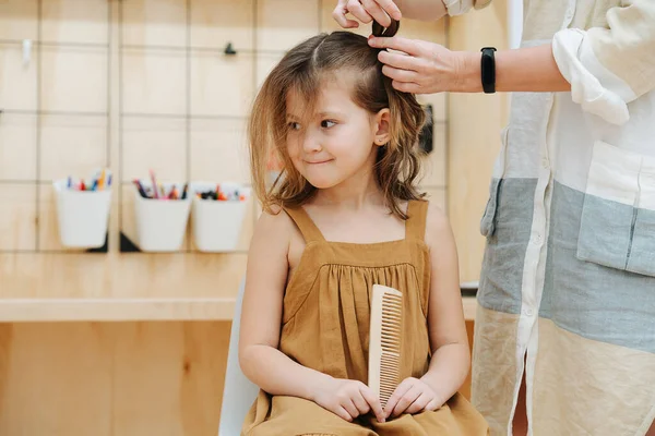 Mom makes pigtails for her daughter in the childrens room — Stock Photo, Image