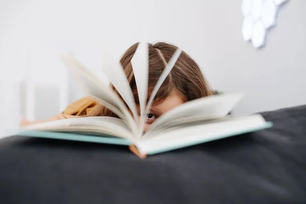 Close-up portret van een 6-jarig meisje, geschoten door een open boek — Stockfoto