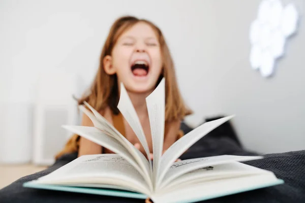 Cheerful emotions of a 6 year old girl, shot through an open book — Stock Photo, Image