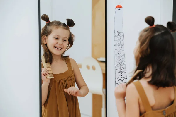 Girl looks after her hair and laughs in front of mirror — 图库照片